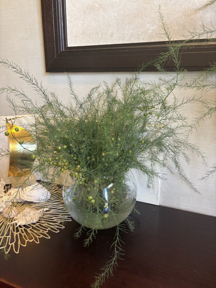 丸いガラスの花器に生けた、窓辺の草花